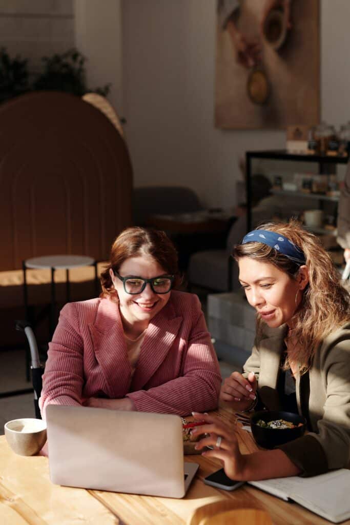 two girls helping each other on the computer 